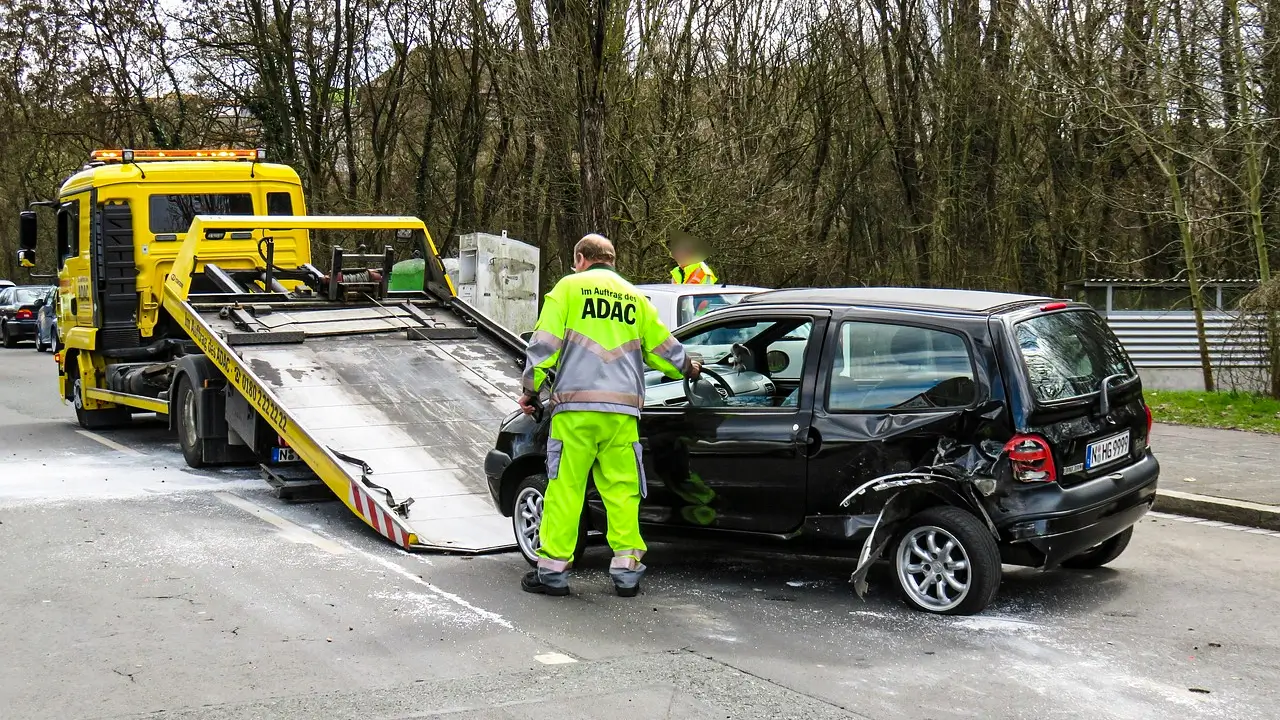 Damaged car being towed after a breakdown, highlighting the importance of preparing your vehicle before a road trip